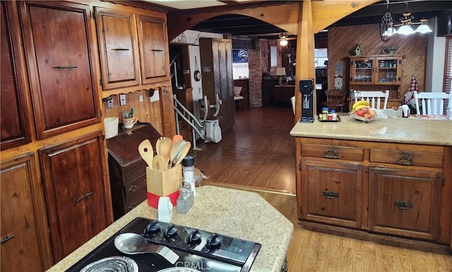 kitchen with light wood-type flooring, wood walls, and decorative light fixtures