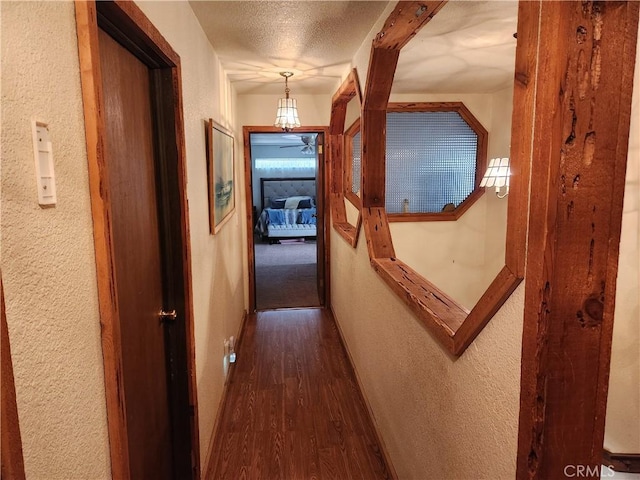 corridor featuring a textured ceiling and dark hardwood / wood-style floors