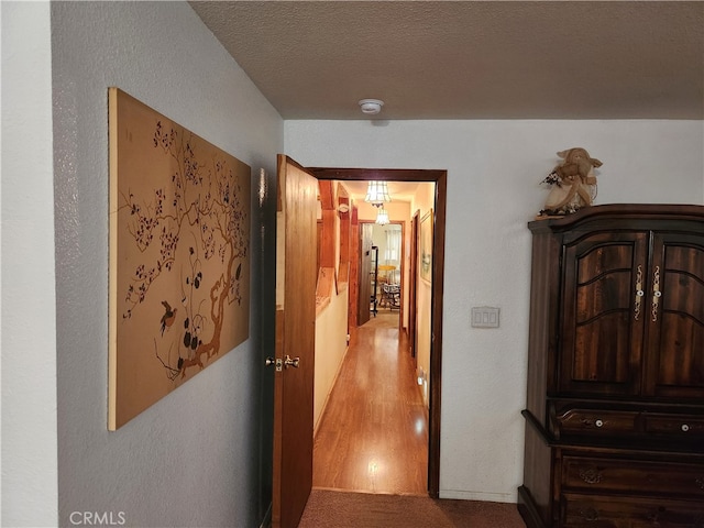 hall with light carpet and a textured ceiling