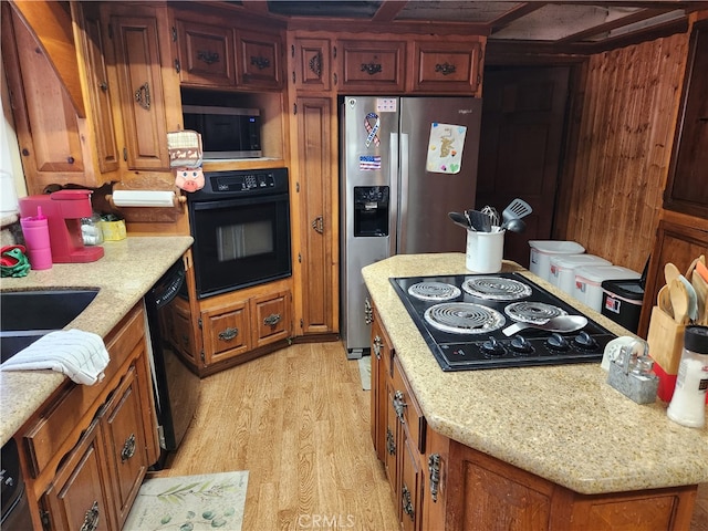 kitchen featuring black appliances, light stone countertops, and light hardwood / wood-style floors