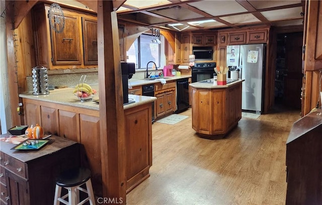 kitchen featuring black appliances, a kitchen island, sink, kitchen peninsula, and coffered ceiling