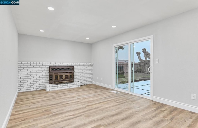 unfurnished living room featuring a brick fireplace and light wood-type flooring