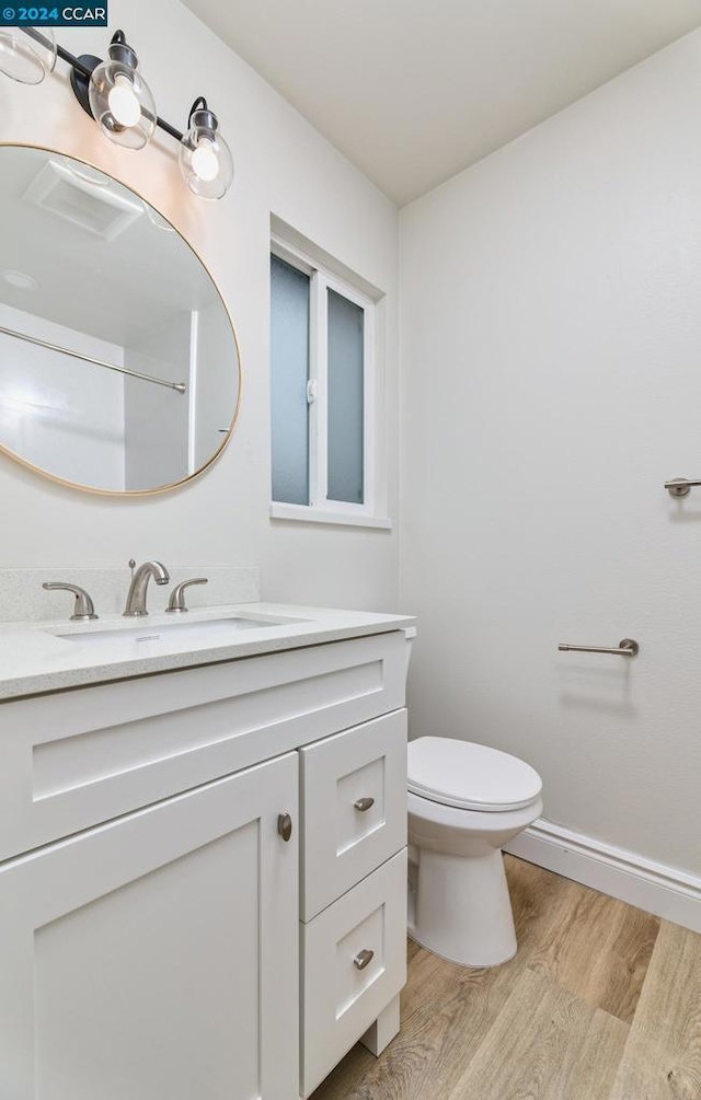 bathroom featuring wood-type flooring, toilet, and vanity