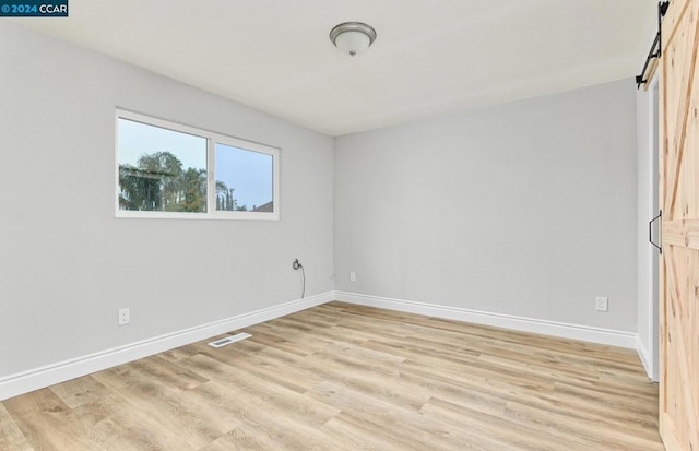 unfurnished bedroom with light wood-type flooring and a barn door