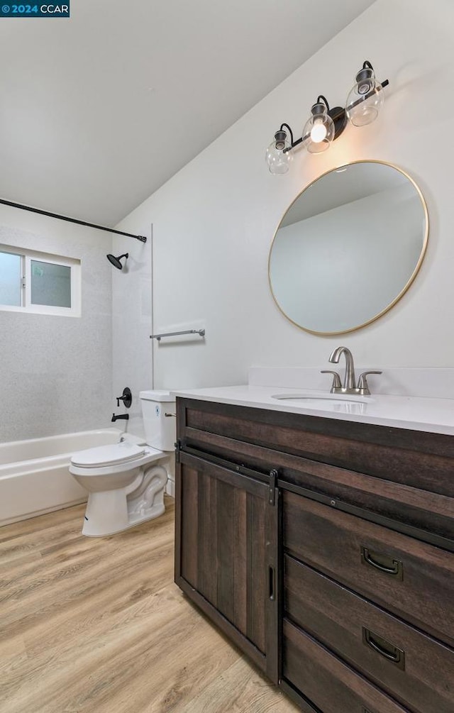 full bathroom with toilet, tiled shower / bath, hardwood / wood-style flooring, and vanity