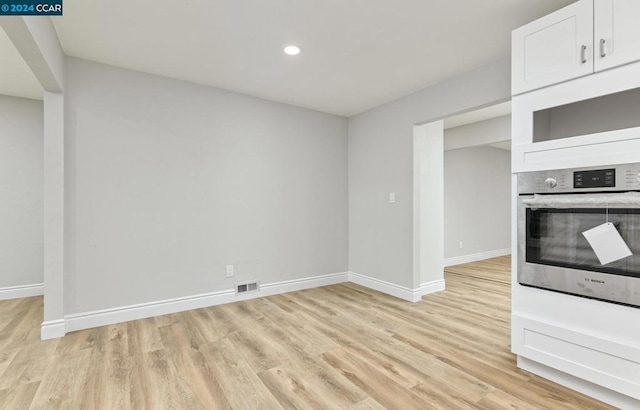 kitchen featuring white cabinetry, light hardwood / wood-style flooring, and stainless steel oven