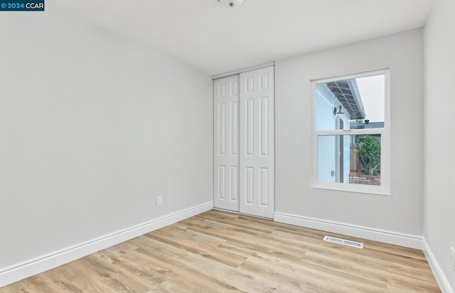 unfurnished bedroom featuring a closet and light hardwood / wood-style flooring