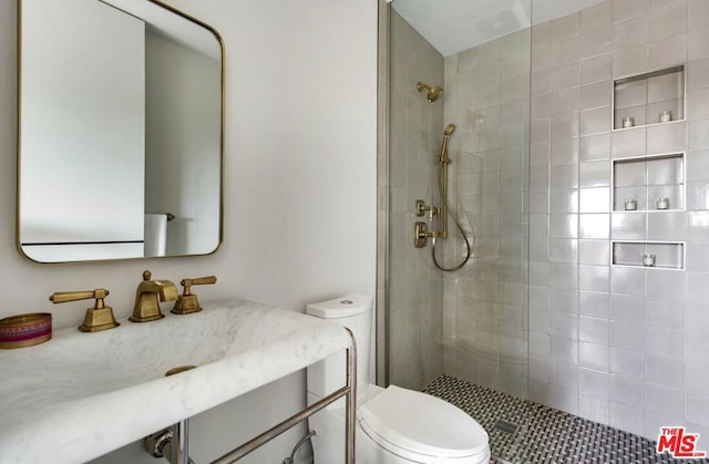 bathroom featuring toilet, tiled shower, and vanity