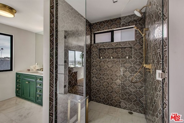 bathroom featuring vanity, a tile shower, and a healthy amount of sunlight