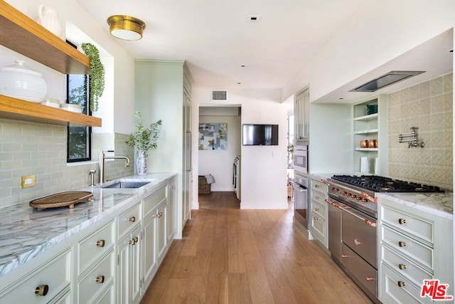 kitchen featuring decorative backsplash, white cabinets, light stone counters, and sink