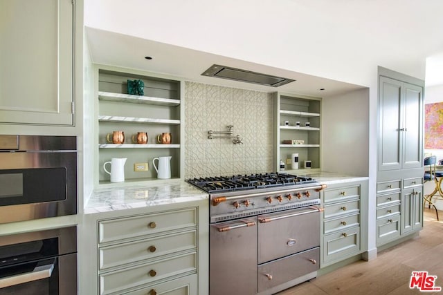 kitchen featuring light wood-type flooring, stainless steel appliances, gray cabinetry, and light stone countertops