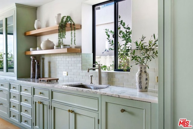 bar featuring tasteful backsplash, plenty of natural light, sink, and light stone counters