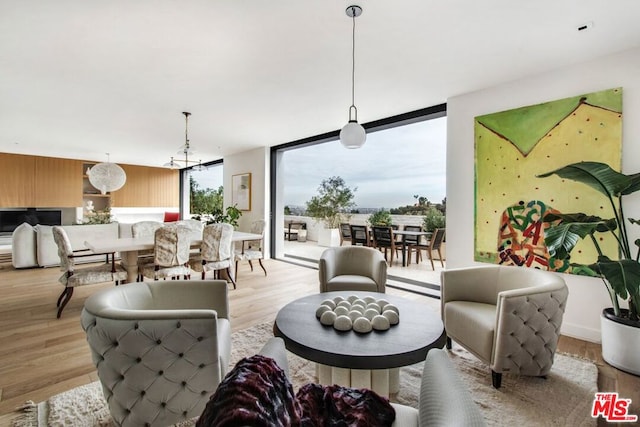 living room with a notable chandelier, floor to ceiling windows, and light hardwood / wood-style floors