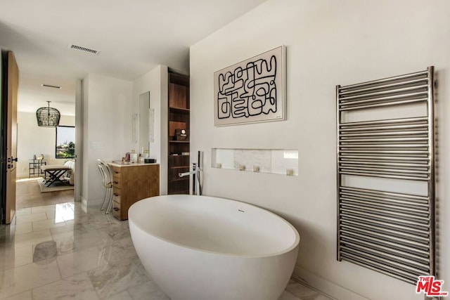 bathroom featuring radiator, a tub to relax in, and vanity