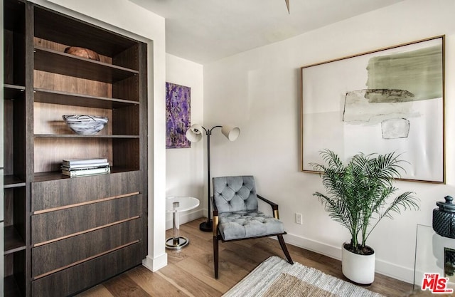 sitting room with hardwood / wood-style flooring and built in features