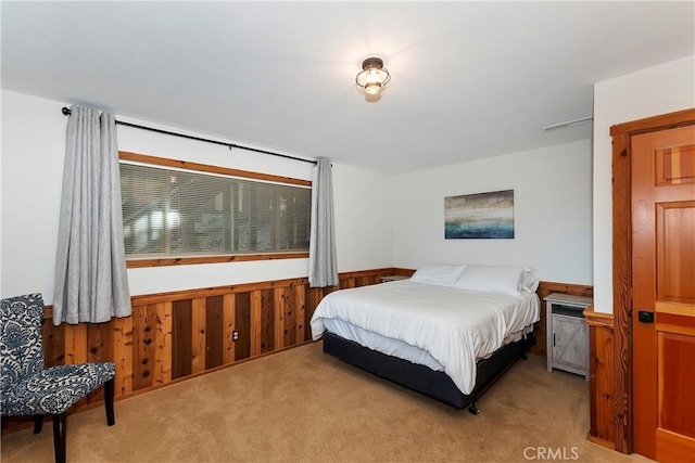 bedroom featuring wood walls and light carpet