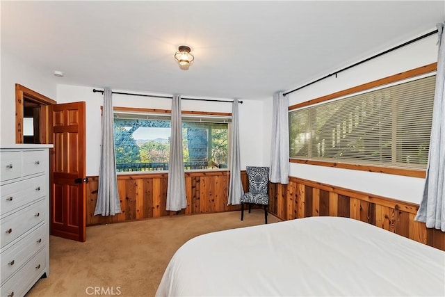bedroom with light carpet and wooden walls