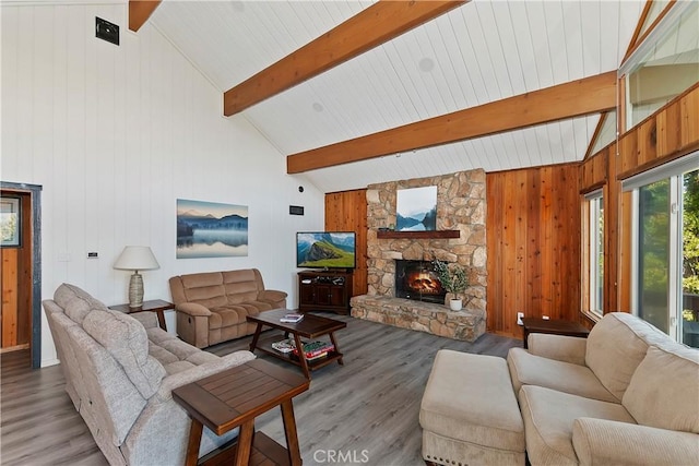 living room featuring wood walls, a fireplace, wood-type flooring, high vaulted ceiling, and beam ceiling