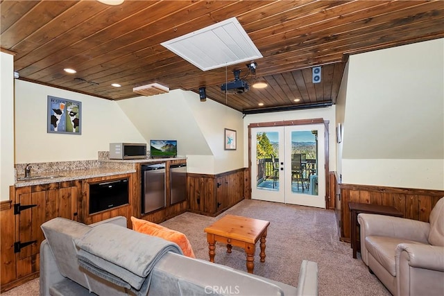 carpeted living room featuring lofted ceiling, wood ceiling, french doors, sink, and wood walls