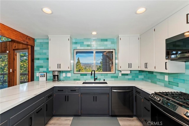 kitchen featuring a healthy amount of sunlight, appliances with stainless steel finishes, sink, and white cabinetry