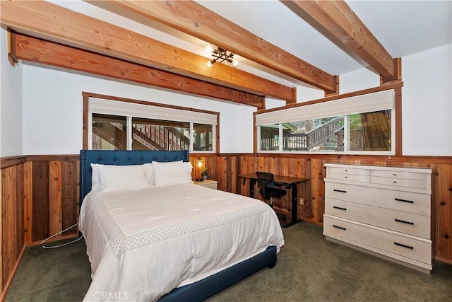 bedroom with wood walls, dark carpet, and beamed ceiling