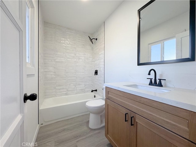 full bathroom with toilet, tiled shower / bath, vanity, and hardwood / wood-style flooring