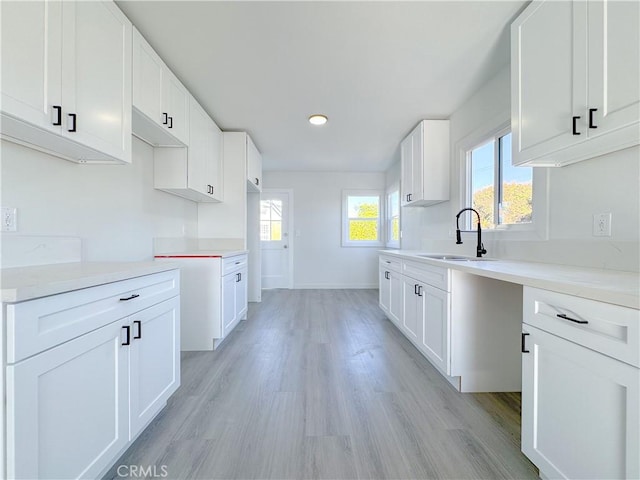 kitchen featuring sink, white cabinetry, light hardwood / wood-style flooring, and a wealth of natural light