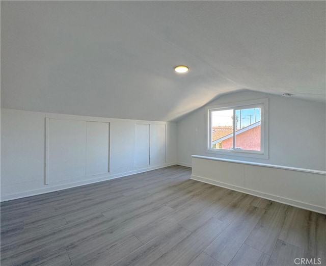 additional living space with lofted ceiling and light hardwood / wood-style floors