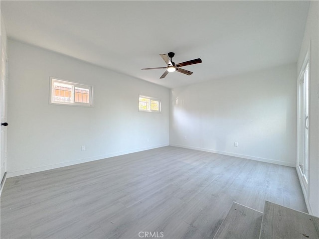 spare room featuring ceiling fan, a healthy amount of sunlight, and light wood-type flooring