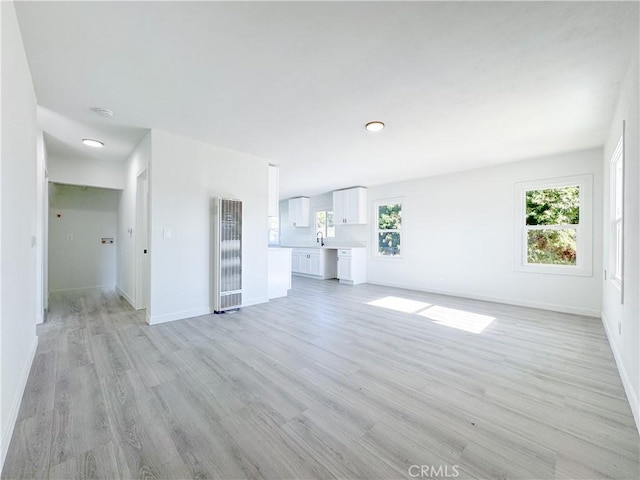 unfurnished living room featuring a healthy amount of sunlight and light hardwood / wood-style flooring