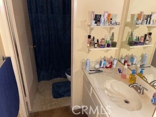 bathroom with toilet, vanity, and curtained shower