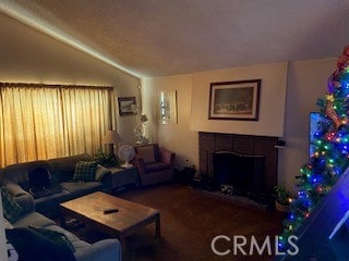 living room with a tiled fireplace and vaulted ceiling