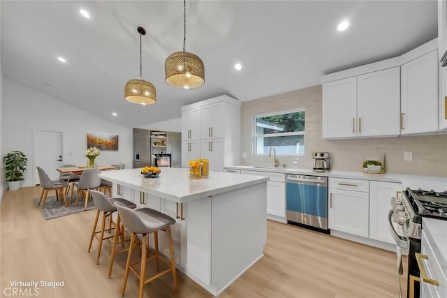 kitchen featuring appliances with stainless steel finishes, decorative backsplash, decorative light fixtures, a kitchen island, and white cabinets