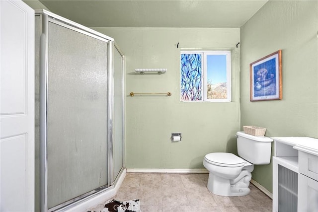 bathroom featuring toilet, a stall shower, tile patterned flooring, and baseboards