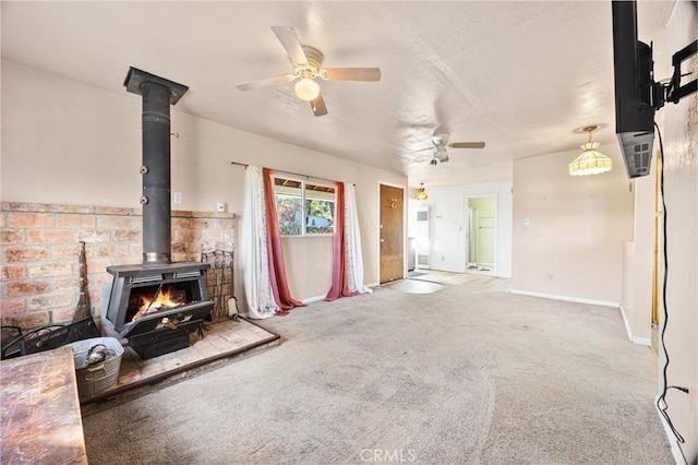 carpeted living room with baseboards, a wood stove, and a ceiling fan