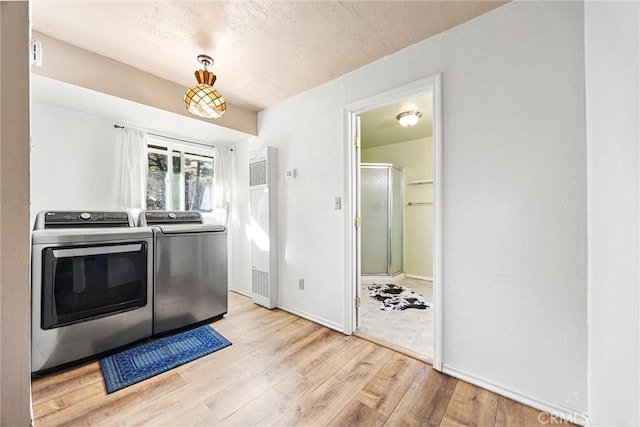 clothes washing area featuring separate washer and dryer and light hardwood / wood-style floors