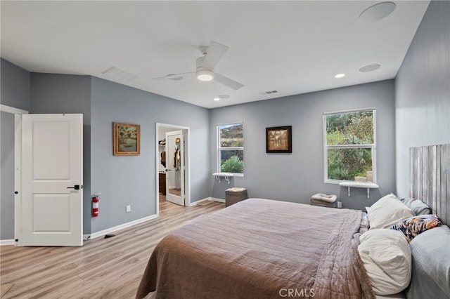 bedroom featuring a spacious closet, ceiling fan, light wood-type flooring, and multiple windows