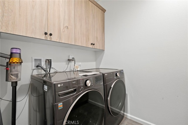 washroom featuring washing machine and clothes dryer and cabinets