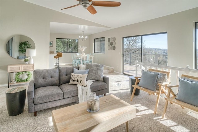 carpeted living room featuring lofted ceiling, a healthy amount of sunlight, and ceiling fan with notable chandelier