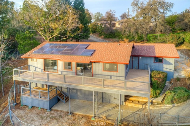 back of property featuring a wooden deck and solar panels