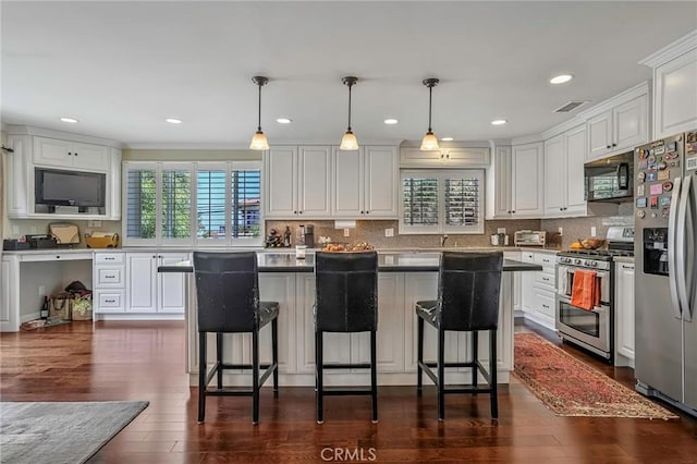 kitchen featuring pendant lighting, white cabinetry, stainless steel appliances, a wealth of natural light, and a kitchen island