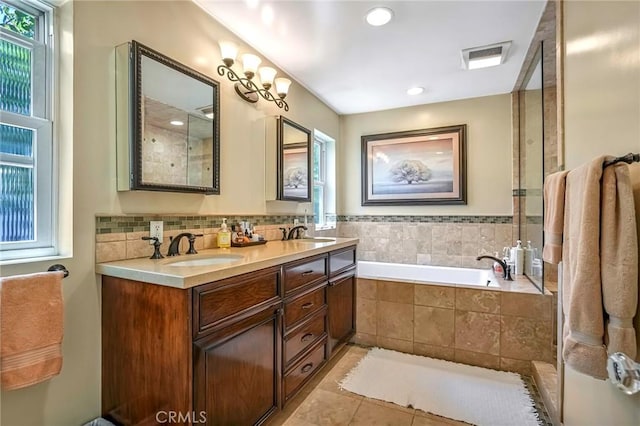 bathroom featuring tile patterned flooring, vanity, plenty of natural light, and tiled bath