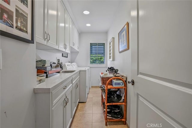 washroom with cabinets, sink, light tile patterned floors, and washing machine and clothes dryer