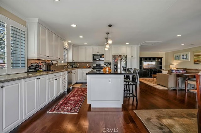 kitchen featuring pendant lighting, stainless steel appliances, dark hardwood / wood-style floors, a center island, and white cabinets