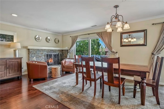 dining area featuring dark hardwood / wood-style floors, a notable chandelier, a fireplace, and crown molding