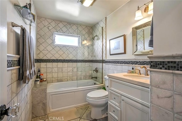 full bathroom with vanity, toilet, tiled shower / bath combo, and tile walls