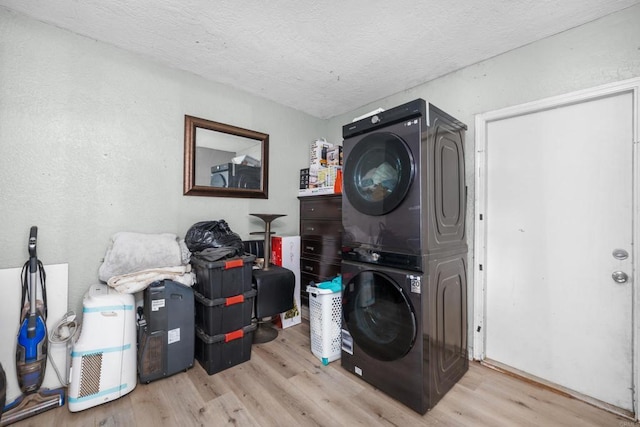 laundry area featuring stacked washing maching and dryer, a textured ceiling, and light hardwood / wood-style flooring