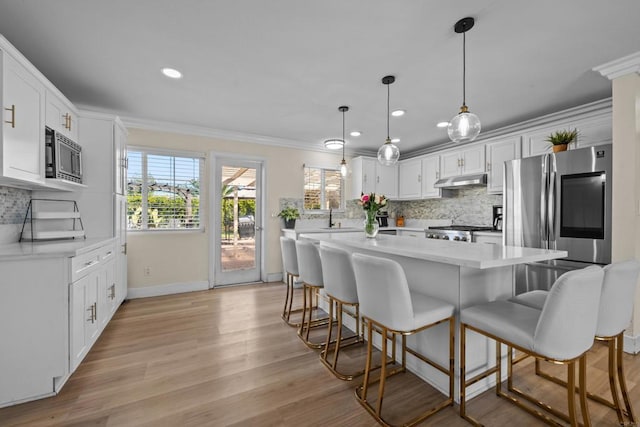 kitchen with appliances with stainless steel finishes, a center island, decorative light fixtures, white cabinetry, and decorative backsplash