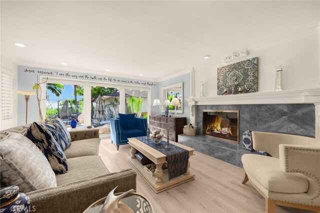 living room featuring hardwood / wood-style floors, crown molding, and a high end fireplace