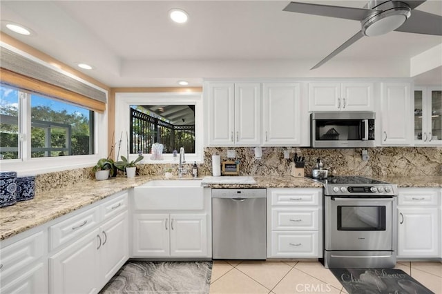 kitchen featuring a sink, white cabinets, appliances with stainless steel finishes, decorative backsplash, and glass insert cabinets